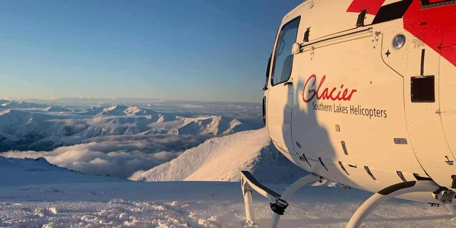 Glacier Southern Lakes helicopter resting on snow in low evening light