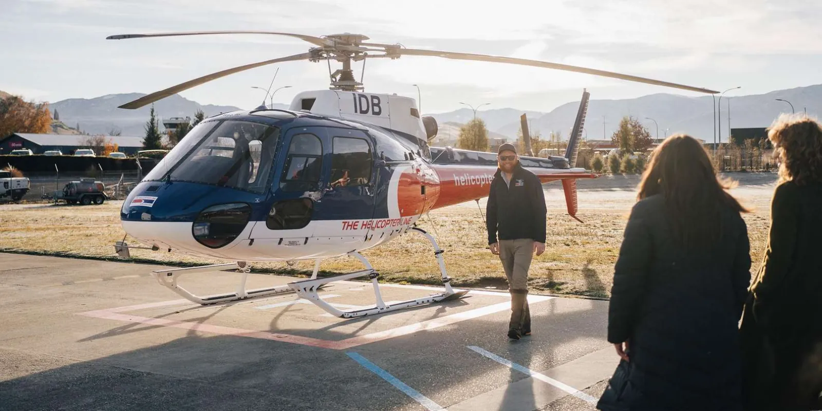Passengers walking out to the helicopter on the pad at the Queenstown Airport base