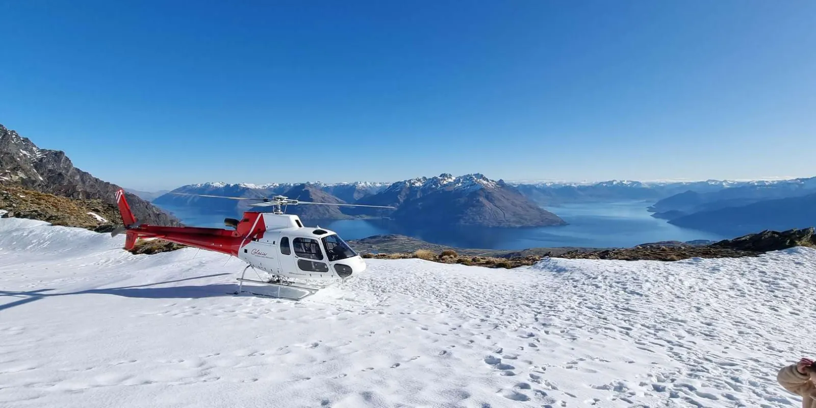 Helicopter parked on a snow-covered ridge high above Lake Wakatipu