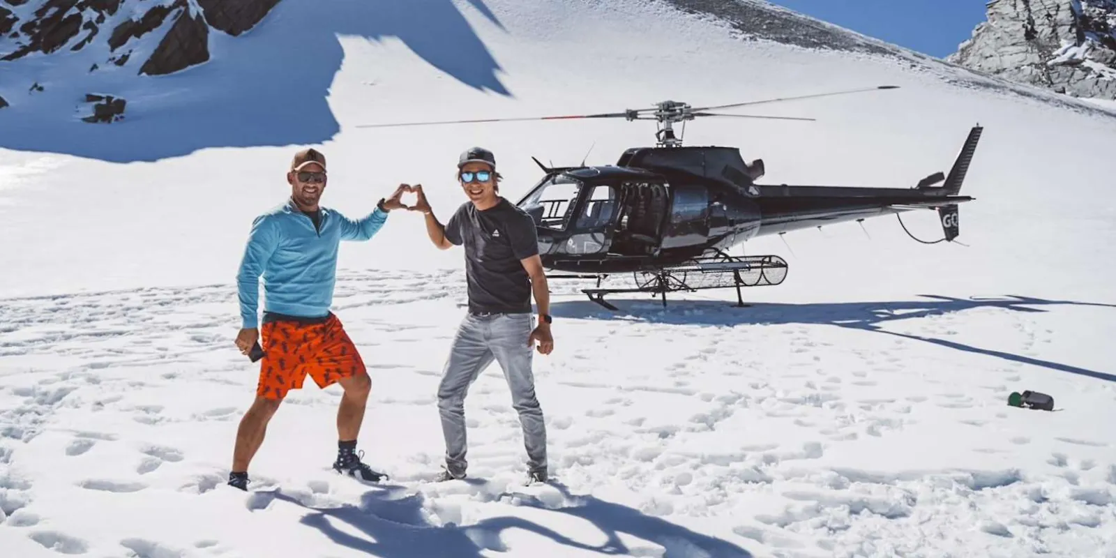 Passengers posing on the snow in front of the parked helicopter